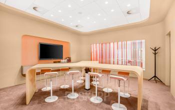 Modern furnished office space at Weena 505, Rotterdam Central Station, featuring a stylish meeting area with high stools around wooden tables.