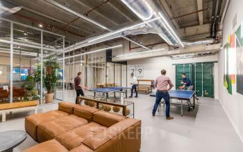 Office space rental at Weena 505, Rotterdam Central Station featuring a modern open floor plan with a ping pong area, sofa, and indoor plants.