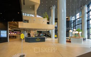 Modern office lobby at Weena 505, Rotterdam Central Station, featuring open seating areas, high ceilings, and a reception desk.