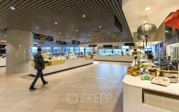 Modern lounge area at Weena 505, Rotterdam Central Station, featuring contemporary design and various food stations, suitable for business meetings and breaks.