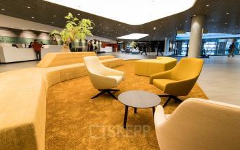 Modern office lounge with yellow and beige seating, located at Weena 505, Rotterdam Central Station.