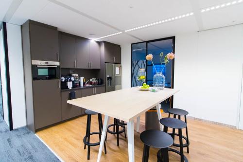 Modern office pantry at Weena 505, Rotterdam Central Station, featuring a kitchenette, tall table with stools, and vibrant decor, perfect for a quick break.
