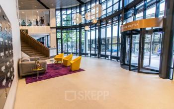 Spacious office reception area at Weena 290, Rotterdam Central Station, featuring modern furnishings and a large window. Ideal for office space rental.