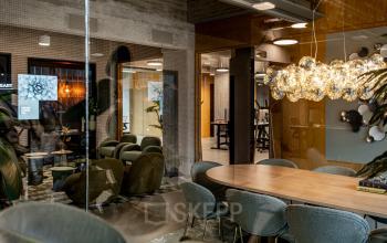 Modern workspace at Hofplein 19, Rotterdam Central Station featuring stylish seating, a chic light fixture, and a collaborative atmosphere, ideal for office space rental.