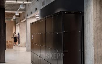 Industrial-style interior of office space rental at Hofplein 19, Rotterdam Central Station, featuring sleek lockers and concrete walls.