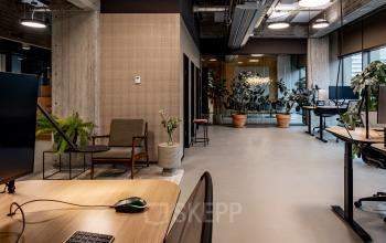 Modern office interior at Hofplein 19, Rotterdam Central Station, featuring open workspaces with desks, plants, and contemporary décor, ideal for office space rental.