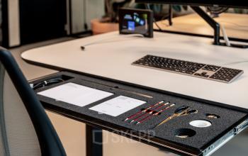 Modern office workspace at Hofplein 19, Rotterdam Central Station, featuring a sleek desk with organized stationery, ideal for office space rental.