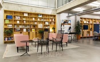 Modern office space at Hofplein 20, Rotterdam Central Station with contemporary furnishings, wooden shelving, and seating area.