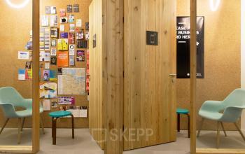 Cozy office space at Hofplein 20, Rotterdam Central Station with modern wooden walls, colorful chairs, and a cork wall full of creative notes.