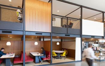 Modern office space rental at Hofplein 20, Rotterdam Central Station, featuring multi-level workspaces with individuals working at desks and collaborating in a cozy, open environment.