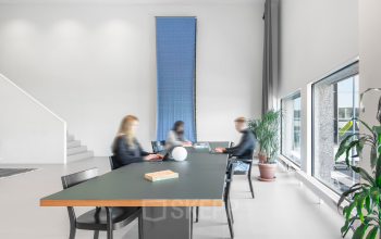 Modern office space rental at Hofplein 20, Rotterdam Central Station, featuring a sleek table with people engaged in business activities.