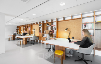 Modern office space for rent at Hofplein 20, Rotterdam Central Station with furnished workspaces and people engaged in business activities.