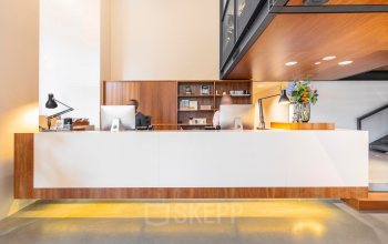 Reception area with a wooden desk and computers at an office in Hofplein 20, Rotterdam Central Station. Ideal for office space rental.