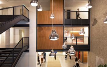 Modern office interior at Hofplein 20, Rotterdam Central Station, featuring stylish lighting, a staircase, and communal walkways. Ideal for office space rental.