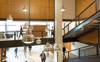 Interior of Hofplein 20 office building at Rotterdam Central Station showing modern workspace with people walking and working.