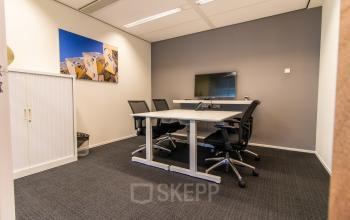 Modern office to rent in Rotterdam Central Station with a meeting table, chairs, and a mounted TV, ideal for office space rental at Weena-Zuid 130.