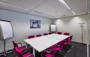 Furnished conference room at Weena-Zuid 130, Rotterdam Central Station, available for office space rental with magenta chairs and white tables.