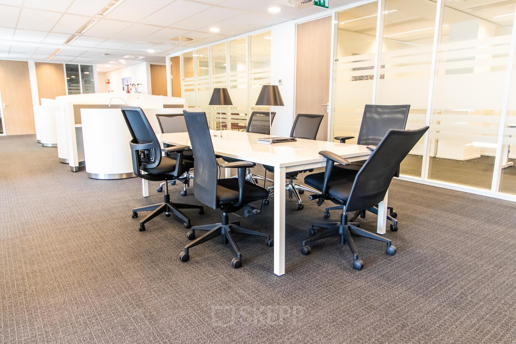 Modern office space rental at Weena-Zuid 130, Rotterdam Central Station featuring a conference table with chairs, ideal for meetings.