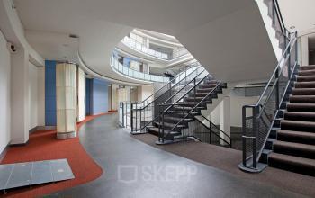 Modern atrium with curved walkways and staircases in the office building located at Kruisplein 15-25, Rotterdam Central Station.