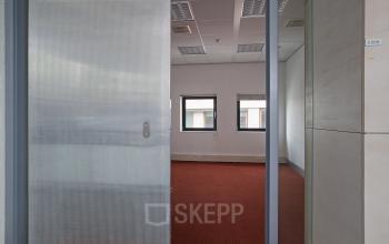 Interior office space at Kruisplein 15-25, Rotterdam Central Station, featuring red carpeting, white walls, and large windows for natural light. Ideal for office space rental.
