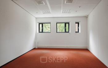 Unfurnished office space with red carpet at Kruisplein 15-25, Rotterdam Central Station, featuring three windows providing natural light.