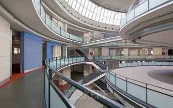 Spacious, modern, multi-level corridor with curved walkways and large windows at Kruisplein 15-25, Rotterdam Central Station, suitable for office space rental.