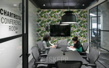 Modern conference room with a black table, surrounded by office chairs, a TV on the wall, and contemporary lighting at Stationsplein 45, Rotterdam Central Station, Rotterdam.