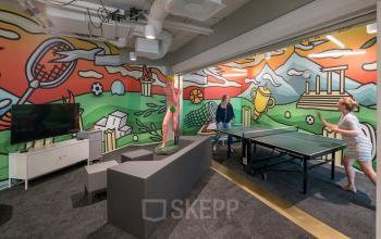 Creative office space rental at Stationsplein 45, Rotterdam Central Station with a bright, mural wall, and a ping pong table.