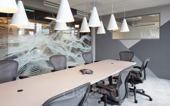 Modern office space for rent at Stationsplein 45, Rotterdam Central Station, featuring a clean conference room with ergonomic chairs, a large meeting table, and contemporary lighting.