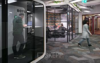 Modern office space rental at Stationsplein 45, featuring glass-enclosed workspaces and a contemporary design inside Rotterdam Central Station.