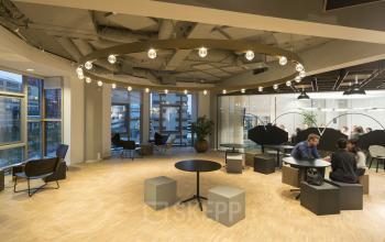 Modern office lounge area at Stationsplein 45, Rotterdam Central Station, with contemporary furniture and large windows, available for office space rental.