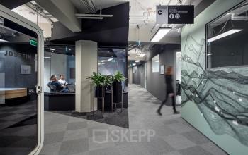 Modern office space at Stationsplein 45 in Rotterdam Central Station featuring sleek design, glass partitions, and indoor plants. Ideal for office space rental.