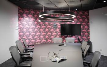 Conference room with modern pink flamingo wallpaper, a large table, and ergonomic chairs in office at Stationsplein 45, Rotterdam Central Station.