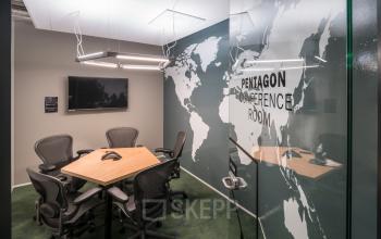 Conference room at Stationsplein 45, Rotterdam Central Station, featuring a world map wall mural, a wooden table, ergonomic chairs, and a wall-mounted TV. Ideal for office space rental.