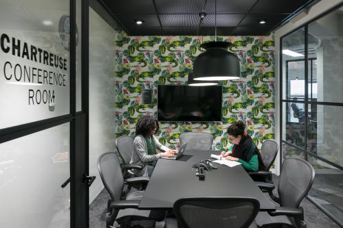 Modern conference room with a black table, surrounded by office chairs, a TV on the wall, and contemporary lighting at Stationsplein 45, Rotterdam Central Station, Rotterdam.