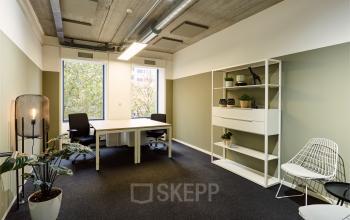 Modern and furnished office space for rent at Westblaak 90, Rotterdam Center, featuring large windows, simple desks, chairs, potted plants, and shelves.