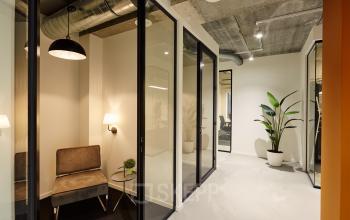 Modern office space interior at Westblaak 90, Rotterdam Center, featuring a small seating area and glass-walled rooms for office space rental.