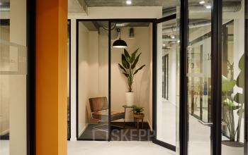 Office space rental at Westblaak 90 in Rotterdam Center featuring modern, glass-enclosed workspaces with seating and indoor plants.