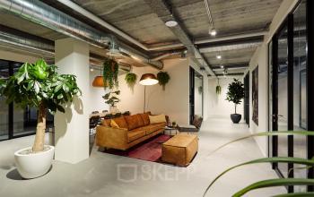 Modern interior of office space for rent at Westblaak 90, Rotterdam Center, featuring stylish lounge area with large sofa, plants, and contemporary lighting.