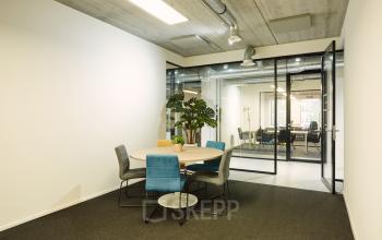 Modern office space at Westblaak 90, Rotterdam Center featuring a round meeting table and glass partitions, ideal for office space rental.
