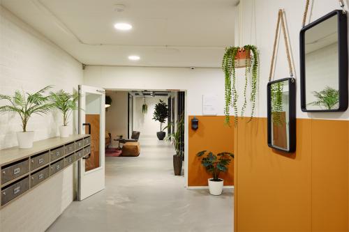 Interior hallway of Westblaak 90 in Rotterdam Center, featuring plants, hanging mirrors, and a seating area in the background. Ideal for office space rental.