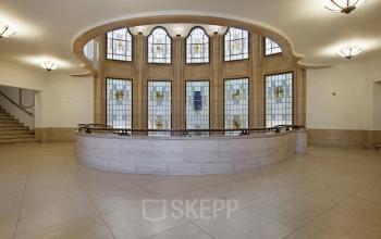 Elegant Schiekade 830 office space rental in Rotterdam Center featuring a spacious lobby with grand staircase and stained glass windows.