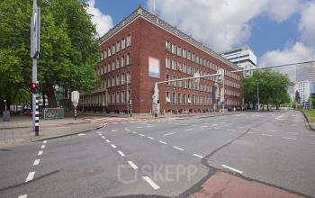 Elegant facade of an office building available for office space rental at Schiekade 830, in Rotterdam Center, under a blue sky with white clouds.
