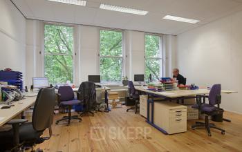 Modern office space rental at Schiekade 830, Rotterdam Center, with large windows and well-lit desks.