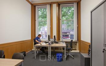 Strategic office space rental at Schiekade 830, Rotterdam Center, with a professional at work overlooking the cityscape.