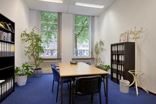 Modern office space rental at Schiekade 830, with a large window, plants, and a meeting table set for collaboration in Rotterdam Center.