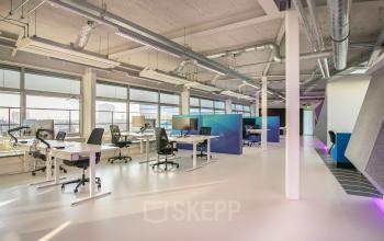 Modern and well-lit office space rental at Vasteland 42-110, in Rotterdam, featuring desks with computers and vibrant color accents.