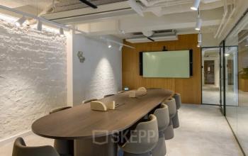 Conference room at Vasteland 42-110, Rotterdam Center with a long table, modern chairs, a flat-screen monitor on the wall, and glass partition.