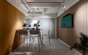 Compact office space with high stools and a wall-mounted TV at Vasteland 42-110, Rotterdam Center, suitable for office space rental.