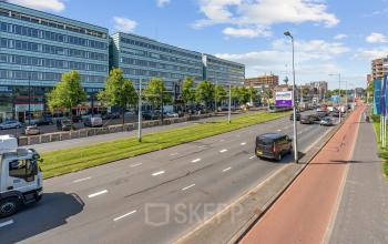 Street view of Vasteland 42-110 in Rotterdam Center showing a modern office building with cars passing by, ideal for those looking to rent office space.